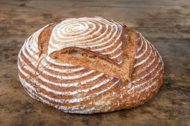 Eski ahşap bir masanın üzerinde büyülenmiş unla taze ekmek.