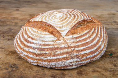 Eski ahşap bir masanın üzerinde büyülenmiş unla taze ekmek.