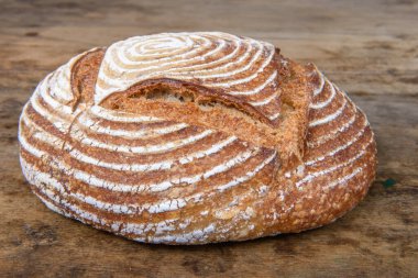 Eski ahşap bir masanın üzerinde büyülenmiş unla taze ekmek.