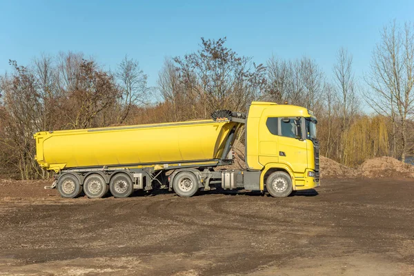 Yellow dump truck on a building site. Truck carrying rocks and earth to build on land