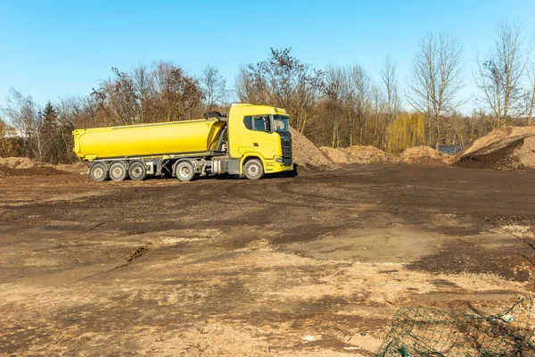 Yellow dump truck on a building site. Truck carrying rocks and earth to build on land