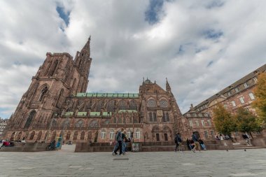 İnsanlar gri sonbahar öğleden sonrasında tarihi binalarla çevrili görkemli Strasbourg Katedrali 'nin önünde yürüyor. Mimarlık birçok turisti cezbeder. Bas Rhin, Alsace, Fransa, Avrupa.