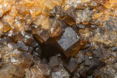 Parlak, açısal kristaller bir kaya parçasında görülebilir. Işık onların dokusunu ve rengini vurgular. Bu mineral oluşumu büyüleyici ve ilgi çekici..