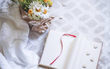 Sevgililer Günü dikey arka planında bir buket kır çiçeği, defter ve kırmızı kalpler var. Sevgililer Günü konsepti. - Evet. Yüksek kalite fotoğraf