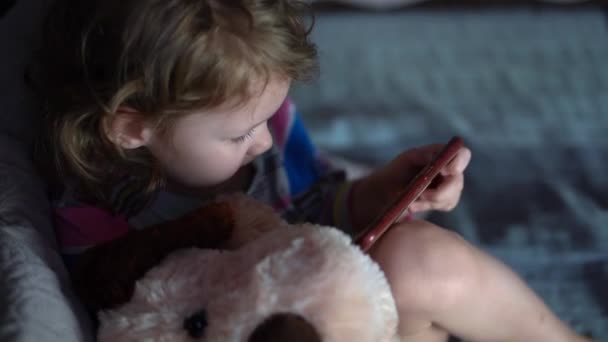 Hija pequeña juega juegos en el teléfono inteligente. — Vídeos de Stock
