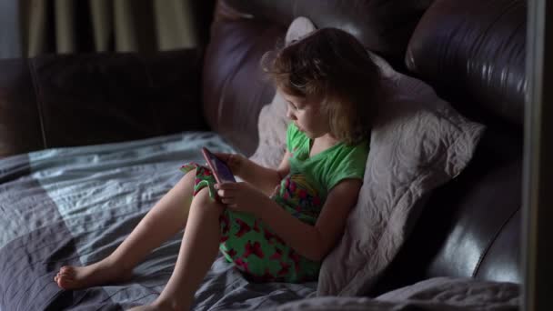 Dívka sledující kreslený film pomocí tabletu. malá dcera hraje hry na smartphone. — Stock video