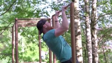 Sakallı, orta yaşlı bir adam kendini yukarı çekiyor. 