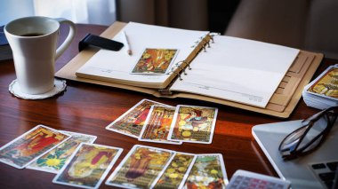 Tarot kartı okuyucusu kartları bir kart dağıtımında düzenler. Masada geleneksel tarot kartlarında fal baktırmak. Seçici odak, Moskova, Rusya-Haziran 2021.