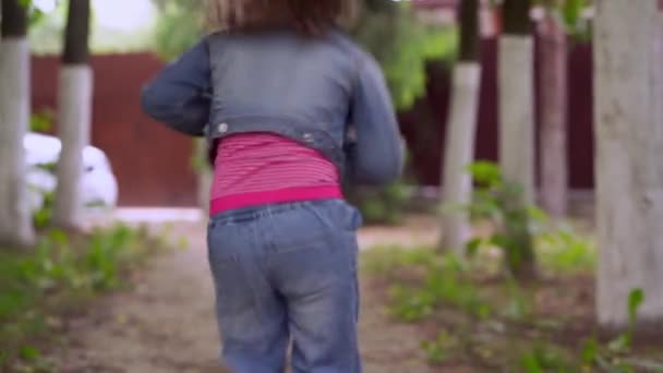 Una piccola bionda riccia felice ragazza di 4-5 anni che corre e salta lungo un percorso. — Video Stock