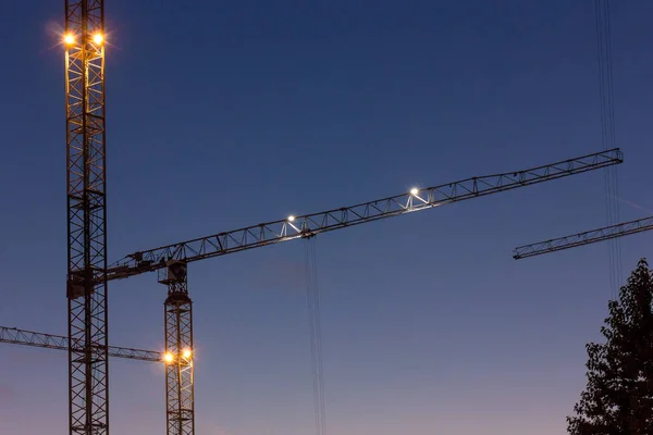 Construction crane in the city while working in new buildings. Evening city landscape. Development concept