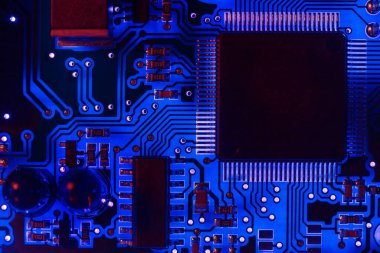 Modern mavi baskılı devre kartının (PCB) bir transistör ve elektronik ekipman işlemcisi arasındaki iletken çizgilerine yakın plan. Programlama, güncelleme ve soyut makro arkaplan bilişim teknolojisi onarımı