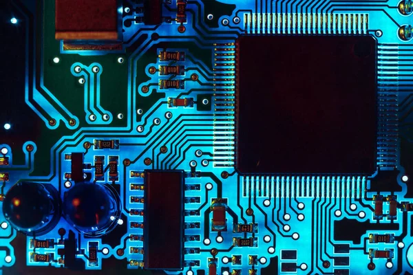 Close-up of a modern blue printed circuit board (PCB) with stripes of conductors between a transistor and an electronic equipment processor. IT technology repair in programming, upgrade and abstract macro background