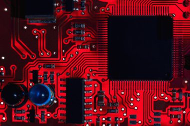 Kırmızı baskılı devre kartının (PCB) transistör ve elektronik ekipman işlemcisi arasındaki iletken çizgilerinin yakın plan görüntüsü. Programlama, güncelleme ve yazılım denetimi konularındaki bilişim teknolojileri soyut arkaplan