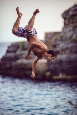Menorca, İspanya - Eylül 8: genç adam uçurumun üzerinden atlama 