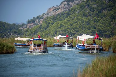 TURKEY, DALYAN, MUGLA - JULY 19, 2014: Touristic River Boats with tourists in the mouth of the Dalyan River clipart