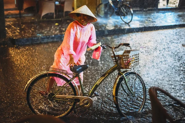 HOI AN, VIETNAM, 28 DE JUNIO: Mujer con bicicleta bajo la lluvia en junio —  Fotos de Stock