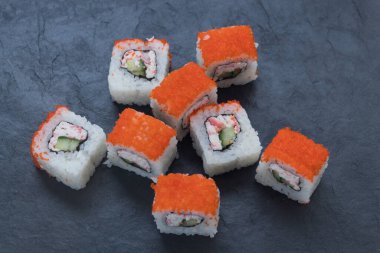 Rolls with salmon on a black stone board. Serve the dish. Serving. Rice, fish, avocado.