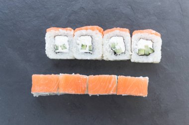 Siyah taş bir tahtanın üzerinde somonla yuvarlanıyor. İki sıra halinde servis yapın. Biri üstte, diğeri de bölümde.