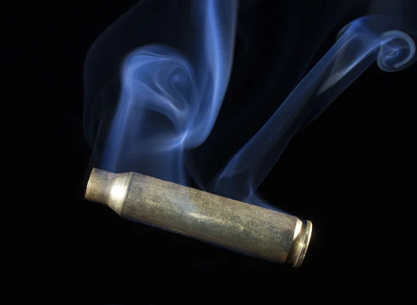 Empty ammunition case that is smoking — Stock Photo, Image