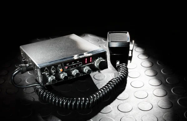 Two-way radio with microphone on a dark background and rubber mat