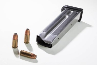 Yarı otomatik tabanca ve beyaz arka planda oyuk uçlu mermili 9 mm 'lik mermiler için çelik şarjörün kenarına gölge..