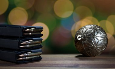 Altın bir aksesuarın ve ahşap bir masanın üzerinde duran tam dolu üç AR-15 şarjörünün arkasında parlayan parlak Noel ışıkları.. 