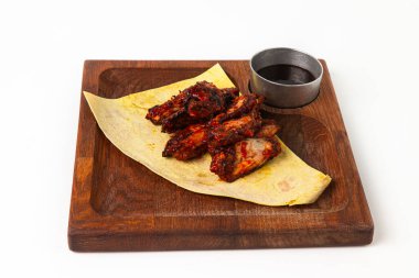 Baharatlı ekmekle servis edilen kızarmış tavuk kanatları, beyaz arka planda kırsal ahşap bir tahtada sunuluyor.