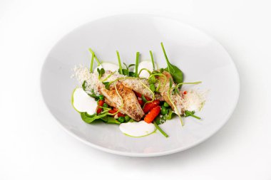 Taze ıspanak, bebek havuç, yeşil bezelye, mikroçerez ve rendelenmiş parmesan peyniri ile servis edilen kurutulmuş balık filetosu.