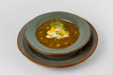 Ekşi krema, yumurta sarısı ve mikro yeşilliklerle süslenmiş lezzetli, zengin yeşil bir çorba.