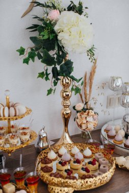 Tatlı büfesi masasında çeşitli tatlı hamur işleri, turtalar ve bir yemek organizasyonu için süslenmiş altın tepsiler sunuluyor.