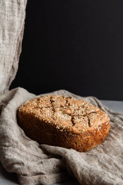 Kırsal ev yapımı ekmek pişirme, doğal keten kumaş üzerinde dinlenen susam tohumlu sağlıklı bir zanaatkar ekmek.