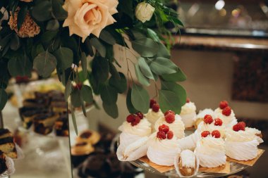 Zarif bir açık büfe sunar leziz tatlı hamur işleri, taze ahududu ve krem şanti ile kaplanmış bireysel pavlovalar dahil