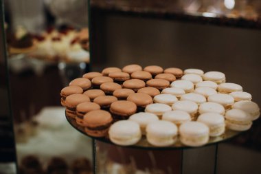 Makarnalar iki tonluk çikolata ve vanilya deseninde dizilmiş. Açık büfede zarif ve tatlı bir görüntü yaratıyorlar.