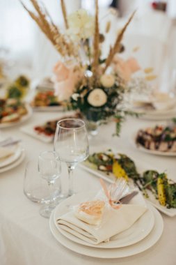 Zarif bir tatil sofrası. Özel bir tatlı ikramı, cam eşyalar, tabaklar ve çiçekli bir süs.