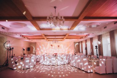 Zarif ziyafet salonu bir resepsiyon partisi için hazırlandı, sehpalar, beyaz sandalyeler ve disko topu ışıklandırması.