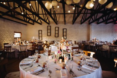 Masalar bir düğün kutlaması için hazırlandı. Zarif yer dekorları, çiçek süslemeleri ve ortam aydınlatması ile sıcak bir atmosfer oluşturuldu.