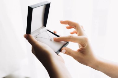 Zarif mücevher kutusunu açan eller pırıl pırıl pırıl elmas bir kolyeyi ortaya çıkarıyor. Lüks, hediye ve özel durumlar kavramı