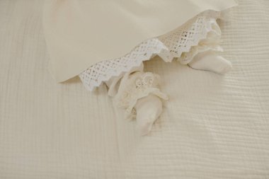 Bebek ayakları ve kumaşlı bir battaniyenin üzerindeki düşük cübbe saflığı, yeni başlangıçları ve dini törenleri sembolize ediyor.