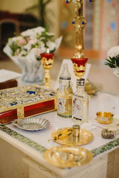 Kilise sunağı masasında Ortodoks Hıristiyan vaftiz ayini için kutsal eşyalar var. Kutsal yağ, kutsal kitap ve mumlar.