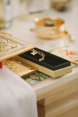 Bir kutuda duran altın haç kolyesi, kilisede kutsal bir Hıristiyan vaftiz ayinine hazır.