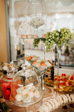 Etkinlik, tatlı barında çeşitli küçük kekler, meyve ve hamur işleri sunuluyor. Zarif cam standlarda sergileniyor.