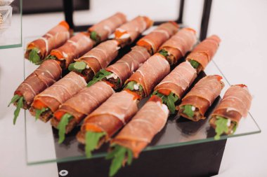 Ekmek, roka ve kırmızı biberli Prosciutto börekleri cam tepside, bir etkinlikte misafirler için hazır.