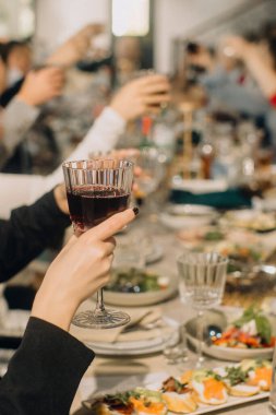 People enjoying a festive dinner gathering, hands raising glasses for a toast. Celebration and togetherness