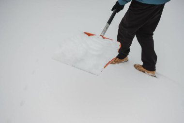 Kışın karlı bir yoldan taze kar küreyerek yolu temizleyen bir insan. Kış bakımı için sıkı çalışma ve çaba
