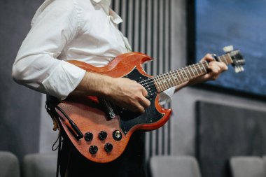 Bir gösteri sırasında elektro gitar çalan bir müzisyen. Elektro gitar gövdesinde tıngırdayan eller