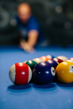 Oyuncu mavi bir keçeli masaya bilardo topu yerleştirerek bilardo oynuyor.