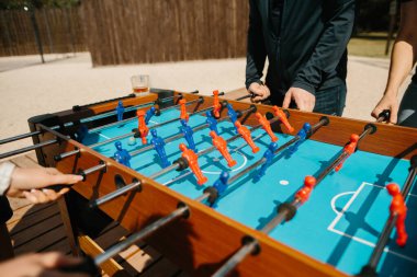 Eller langırt çubuklarını kavrıyor, arkadaşlar boş zamanlarında rekabetçi masa futbolu oynuyorlar.