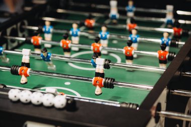 Langırt oyuncuları metal çubuklara konumlanmış, yeşil alanda hareketlilik gösteriyorlar. Bir sıra oyun topu oyunu bekliyor