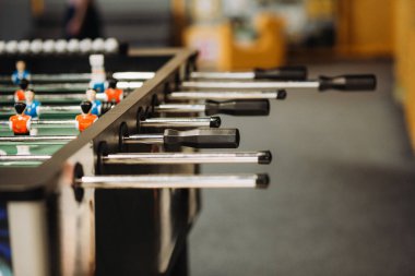 Siyah oyuncu kulpları ve minyatür kırmızı ve mavi futbol oyuncularının yer aldığı langırt masası oyunu, eğlence ve eğlenceyi destekliyor