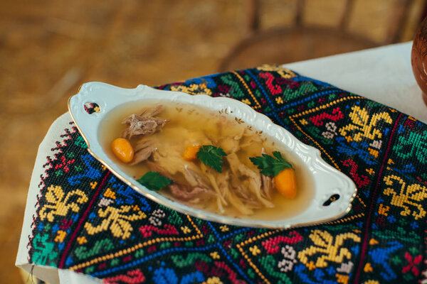 Ukrainian kholodets, a traditional meat jelly with pork and carrots, served in an ornate dish on a vibrant embroidered rushnyk